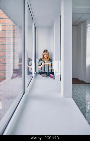 Student sitting at the window in hallway learning Stock Photo