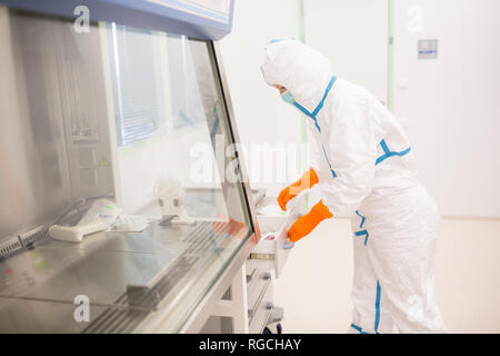 Lab technician wearing cleanroom overall in laboratory for drug production