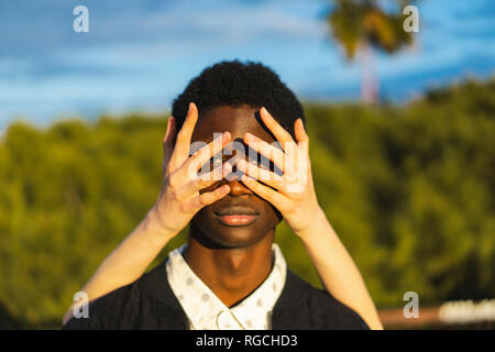 Hands covering eyes of a young black man Stock Photo