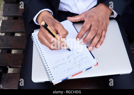 Businessman writing notes in notebook, close-up Stock Photo