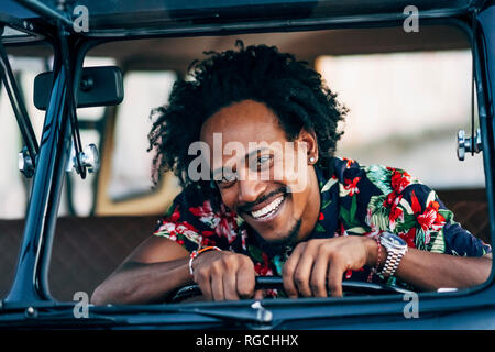 Portrait of laughing man looking out of car window Stock Photo