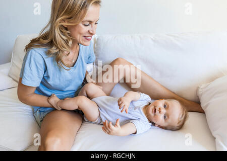 Happy mother playing with her baby girl on couch Stock Photo