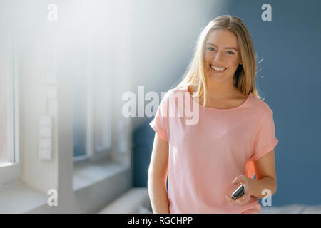 Portrait of smiling young woman with cell phone in her hand Stock Photo