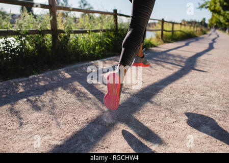 Legs of sportive woman running on path Stock Photo
