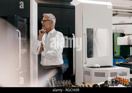 Manager in high tech company thinking, with hand on chin Stock Photo