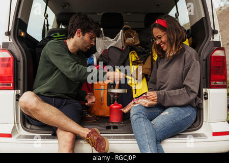 Young couple preparing sausages on a camping stove Stock Photo