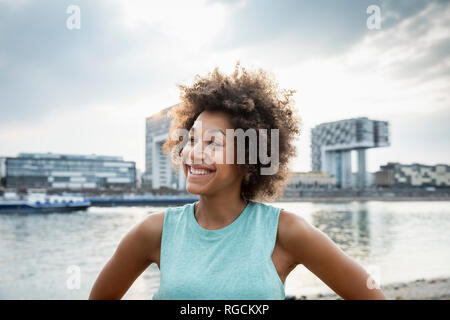 Germany, Cologne, portrait of happy woman at River Rhine