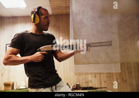 Man shooting with a rifle in an indoor shooting range Stock Photo