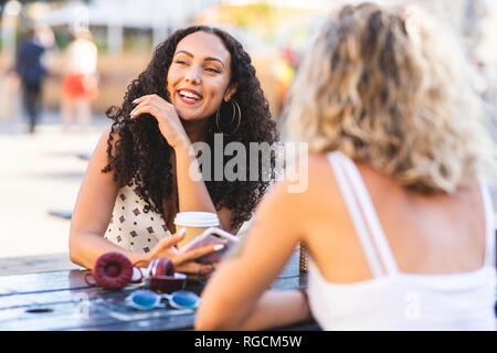Two happy friends talking together at table outdoors Stock Photo