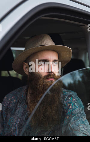 Bearded young man looking out of car window Stock Photo