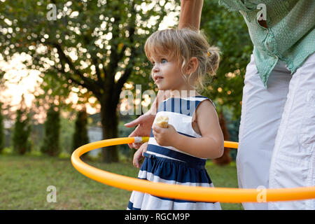 Grandmother and granddaughter playing together in garden with hoola hoop Stock Photo