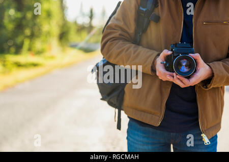 Finland, Lapland, close-up of man holding camera on country road Stock Photo