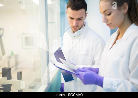 Man and woman in lab coats with clipboards Stock Photo