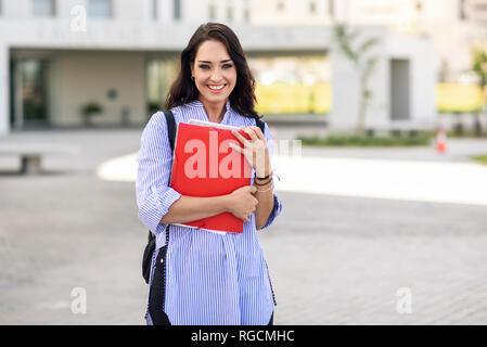 Portrait of happy student with notebooks on campus Stock Photo