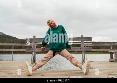 Finland, Lapland, woman stretching on jetty at a lake Stock Photo