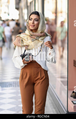 Spain, Granada, young Arab tourist woman wearing hijab, using fotocamera during shopping in the city Stock Photo