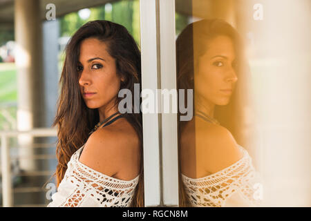 Portrait of young woman leaning against a window Stock Photo