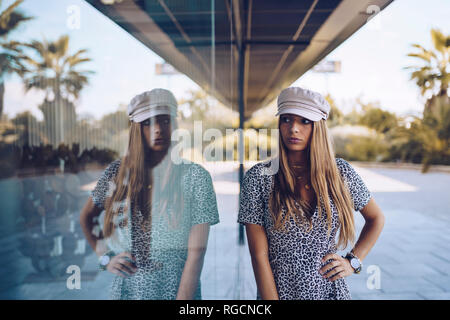 Attractive young woman in leopard print dress reflected in windowpane Stock Photo