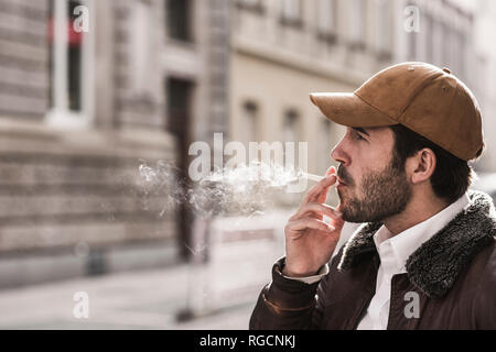 Portrait of young man with baseball cap smoking cigarette Stock Photo