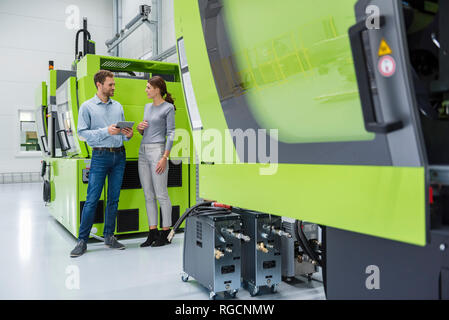 Colleagues in high tech company controlling manufacturing machines, using digital tablet Stock Photo