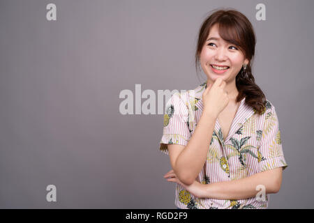 Portrait of young happy Asian tourist woman smiling and thinking Stock Photo