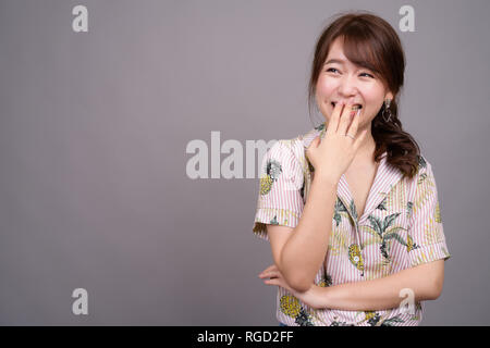 Portrait of young beautiful Asian tourist woman laughing Stock Photo