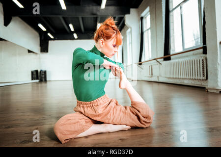 Young red-haired yoga instructor with hair bun looking involved Stock Photo