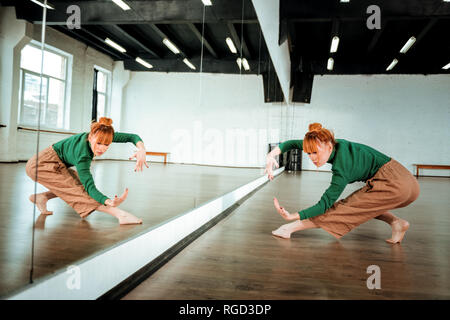 Pretty red-haired professional dancer dancing near the mirror Stock Photo