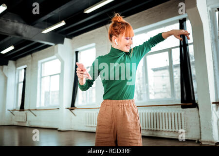 Red-haired professional yoga instructor in a green turtleneck smiling positively Stock Photo