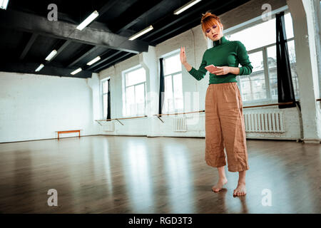 Red-haired professional yoga instructor with hair bun looking serious Stock Photo