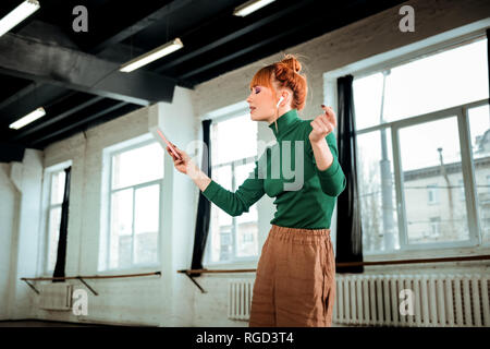 Red-haired professional yoga instructor with hair bun listening to music Stock Photo