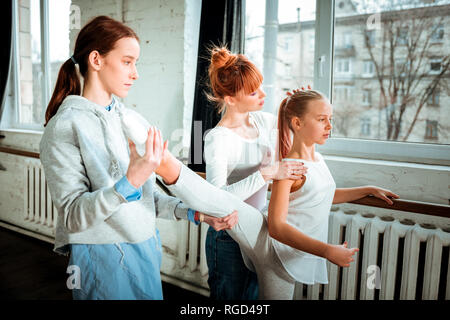 Red-haired gymnastics teacher in a white shirt correcting her students back position Stock Photo