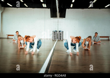 Red-haired ballet teacher in blue jeans showing movements to her students Stock Photo