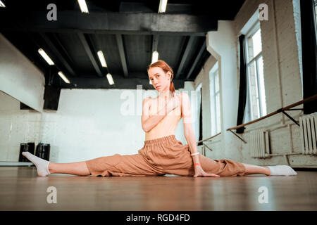 Cute red-haired teenager in orange pants looking thoughtful Stock Photo