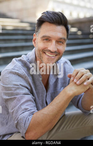 Portrait of laughing mature man   sitting on stairs Stock Photo