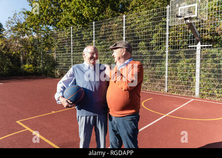 Two fit seniors having fun on a basketball field Stock Photo