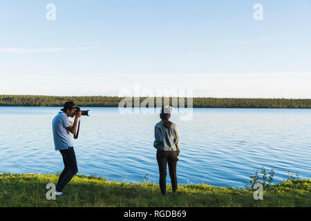 Young man taking pictures of young woman at a alake Stock Photo