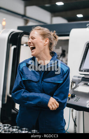 Young woman working as a skilled worker in a high tech company, laughing Stock Photo