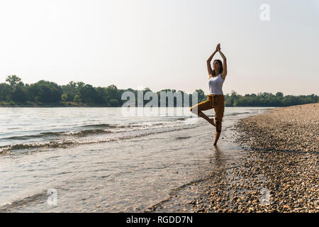 Young woman standing in water of a river practicing yoga Stock Photo