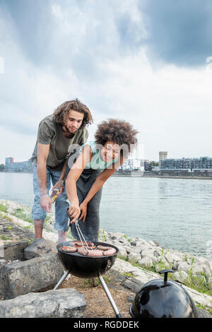 Germany, Cologne, couple having a barbecue at the riverside Stock Photo