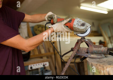 Craftswoman using angle grinder in her workshop Stock Photo