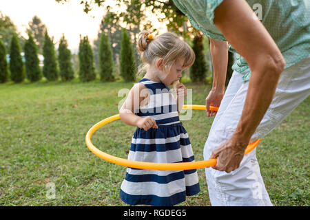 Grandmother and granddaughter playing together in garden with hoola hoop Stock Photo