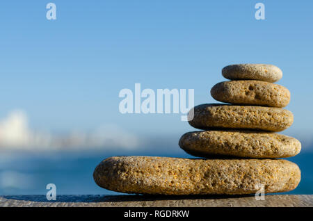 A stone cairn constructed from beach pebbles with the city of Durban, South Africa, in the backgraound. Stock Photo