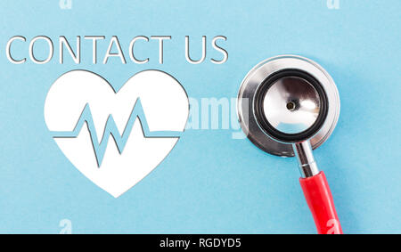 Contact us concept text with stethoscope and heart symbol with cardiogram drawing on blue background Stock Photo