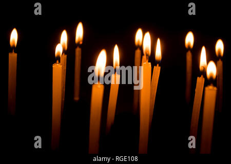 Many christmas candles burning at night on the black background. Candle flame set isolated in black background. Group of burning candles in dark with 
