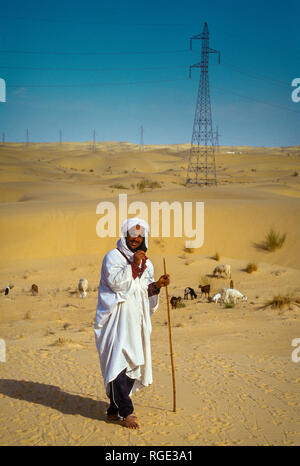 BORDJ EL HAOUAS, ALGERIA - JANUARY 16, 2002: unknown shepherd of goats in the middle of the desert Stock Photo