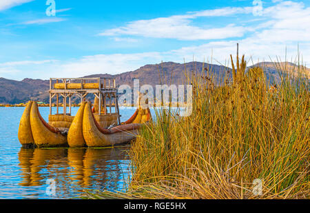 A totora reed boat by the Uros floating islands at sunrise with the Andes mountain range in the background near Puno, Peru, South America. Stock Photo
