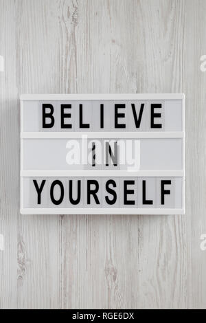 'Believe in yourself' words on lightbox on a white wooden surface, top view. From above, flat lay, overhead. Stock Photo