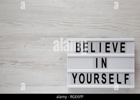 'Believe in yourself' words on lightbox on a white wooden surface, top view. From above, flat lay, overhead. Copy space. Stock Photo