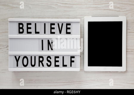Lightbox with text 'Believe in yourself', tablet on a white wooden surface, top view. From above, flat lay, overhead. Stock Photo